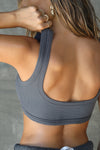 Close up back view of model posing in the fitted and stretchy smoke flexrib Scoop Neck Bra top with a scoop back