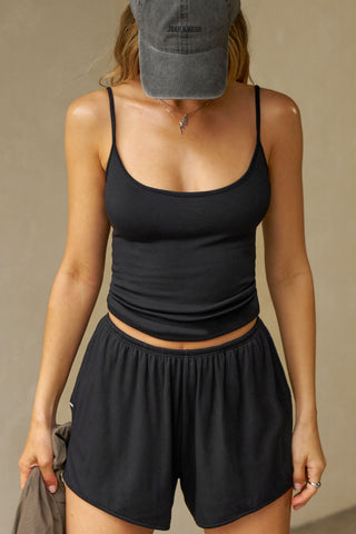 Front view of model posing in the relaxed-fit black modal Easy Short with an elastic waistband, side pockets and subtle pleating for added shape and dimension