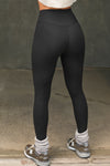 Back view of model from the waist down posing the full length and high-waisted sueded onyx Second Skin Legging with a wide, v-shaped waistband