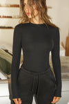 Font view of model posing in fitted black flexrib Sheer Back Long Sleeve top with a crew neckline and sheer mesh back panel.
