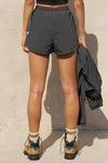 Back view of model from the waist down posing in the relaxed-fit jet nylon Classic Track Short with an elastic waistband, side seam pockets, and adjustable drawcord.