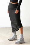 Front view of model from the waist down posing in the midi length black modal Cinched Skirt with adjustable side cinching