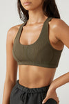 Close up front view of model posing in the fitted stretchy army flexrib Stitch Bra top with a scoop neckline and stitched detailing at the bust