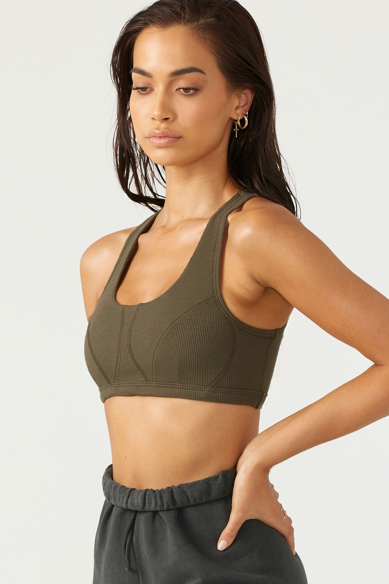 Front view of model posing in the fitted stretchy army flexrib Stitch Bra top with a scoop neckline and stitched detailing at the bust