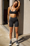 Full body front view of model posing in the stretch high-waisted sueded onyx 4 Inch Body Short with slimming and contouring wide waistband and 4 inch inseam.