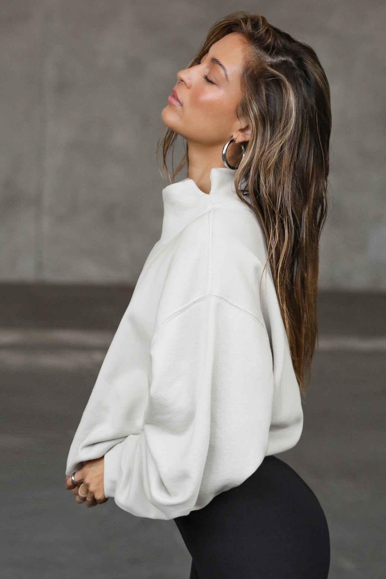 Side view of model posing in the comfortable sahara french terry Turtleneck Sweatshirt pullover with a side split in the collar and a slightly oversized fit