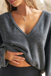 Close up detail front view of model posing in the slouchy storm sherpa V Neck Pullover sweatshirt with a wide V-neckline that can be worn on or off the shoulders.