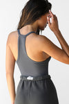 Back view of model posing in the fitted stretchy smoke flexrib V Neck Racerback Tank with a narrow racerback silhouette and thin straps