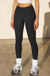 Front view of model from the waist down posing in the sleek and stretchy full length sueded onyx The Body Legging with a mid-rise elastic waistband