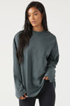 Front view of model posing in the oversized evergreen cotton Vintage Long Sleeve top with a crew neckline and ribbed accents