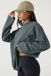Side view of model posing in the oversized evergreen cotton Vintage Long Sleeve top with a crew neckline and ribbed accents
