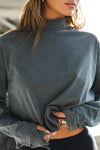 Close up front view of model wearing the relaxed fit evergreen cotton Vintage Turtleneck Long Sleeve Top with thumbholes and torn seams at the cuff