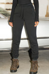 Front view of model from the waist down posing in the tapered black french terry Empire Jogger with side pockets and an elastic waistband and ankle cuffs