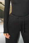Close up detail front view of model from the waist down posing in the tapered black french terry Empire Jogger with side pockets and an elastic waistband and ankle cuffs