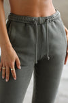 Close up detail front view of model from the waist down posing in the tapered washed sage french terry Empire Jogger with side pockets and an elastic waistband and ankle cuffs