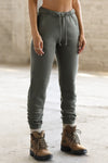 Front view of model from the waist down posing in the tapered washed sage french terry Empire Jogger with side pockets and an elastic waistband and ankle cuffs