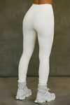 Back view of model from the waist down posing in the stretchy high-waisted bone flexrib Essential Legging with boxer-style stitching, cuffed ankles and an elastic waistband
