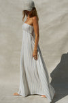 Side view of model posing in the relaxed-fit lightweight natural white and blue stripe gauze Essential Maxi Dress with a straight neckline, fitted bodice and removable adjustable straps 