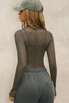 Back view of model posing in the fitted and sheer graphite mesh Exposed Seams Long Sleeve top with a mock neckline and exposed seam details