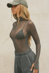 Side view of model posing in the fitted and sheer graphite mesh Exposed Seams Long Sleeve top with a mock neckline and exposed seam details