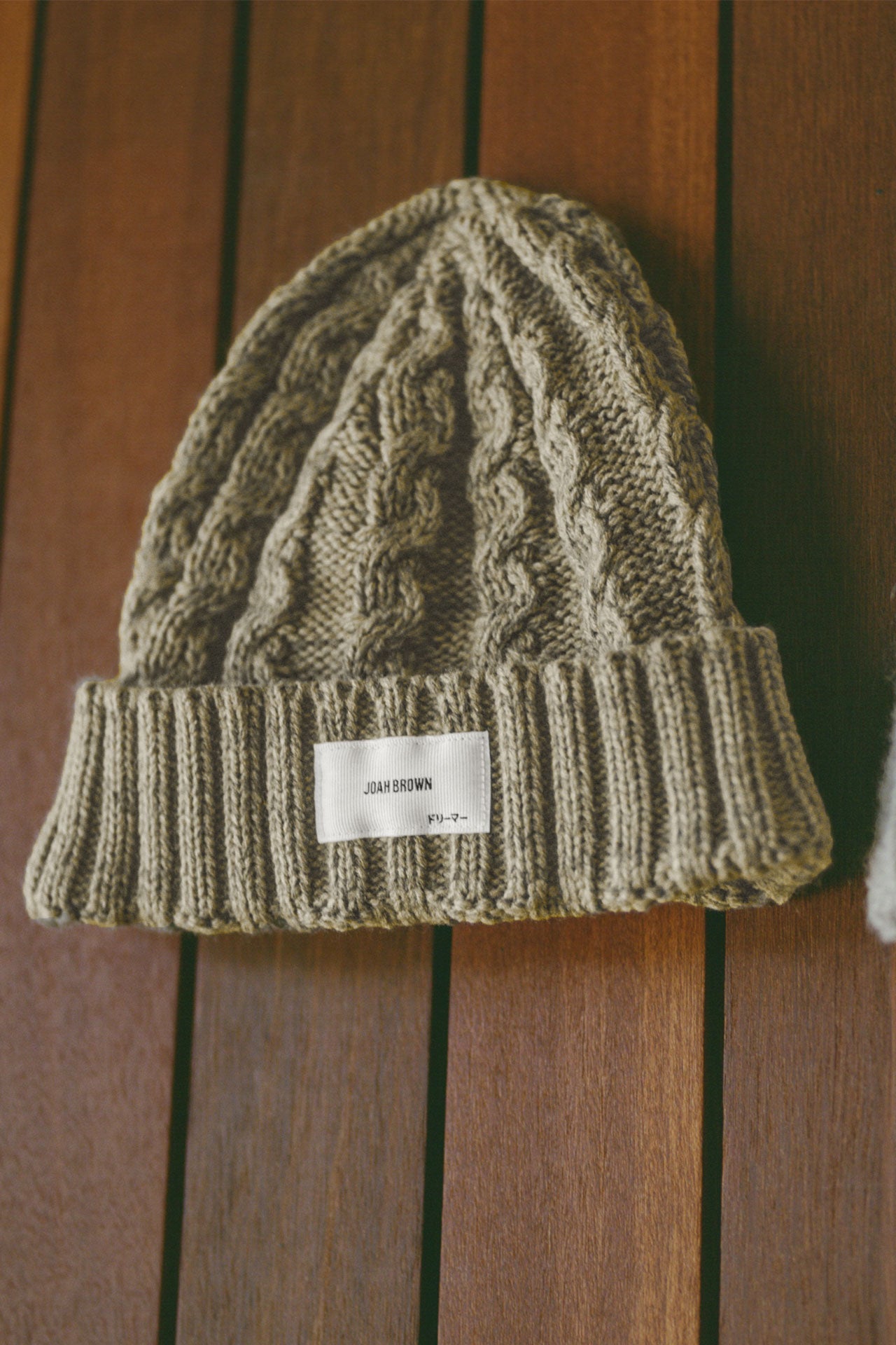 Front flat lay view of the soft and warm moss Cable Knit Beanie that has a custom JOAH BROWN  dreamer logo patch on the front