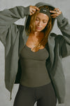 Front view of model posing in the oversized comfortable washed sage french terry Oversized Zip Hoodie with a full length front zip closure, side pockets and thumbholes in the fitted cuffs