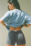 Back view of model posing in the high waisted washed black french terry Fitted Sweat Short with an elastic waistband