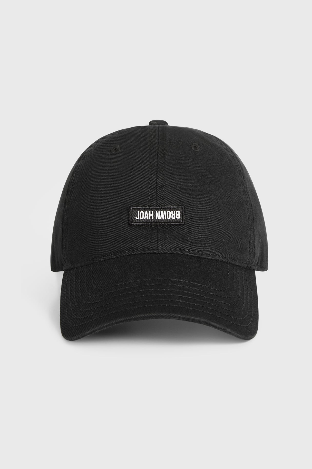 Flat lay fornt view of the six-panel black Signature Cap with a curved brim and a custom upside down Joah Brown logo patch on the front