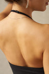 Close up detail back view of model posing in the fitted and smoothing sueded onyx Halter Scoop Tank with a scoop neckline, open back and narrow, adjustable neck strap. 