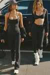 Two models posing outside in front of a car in sueded onyx tops and leggings