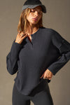 Front view of model posing in the relaxed-fit midnight luxe knit Henley Pullover long sleeve top with a buttoned henley neckline and curved hem.