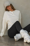 Front view of model posing in the relaxed-fit natural luxe knit Henley Pullover long sleeve top with a buttoned henley neckline and curved hem.