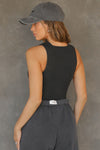 Back view of model posing in the fitted and stretchy vintage black flexrib High Square Neck Tank top with a high square neckline