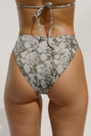 Close up back view of model from the waist down posing in the meadow camo High-Waisted Bikini Bottom with a full back coverage bottom and high-cut legs