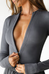 Close up detail front view of model wearing the form fitting smoke flexrib Invisible Zip Long Sleeve top with a 3/4 front invisible zipper and a crew neckline