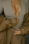 Close up front view of model posing in the form fitting taupe flexrib Invisible Zip Long Sleeve top with a 3/4 front invisible zipper and a crew neckline