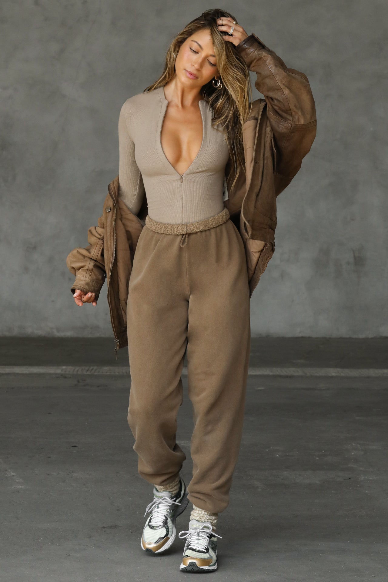Full body front view of model posing in the form fitting taupe flexrib Invisible Zip Long Sleeve top with a 3/4 front invisible zipper and a crew neckline