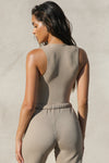 Back view of model posing in the form fitting taupe flexrib Invisible Zip Tank top with a front invisible zipper and a crew neckline