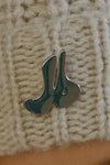 Close up detail front view of the custom  removable JOAH BROWN pin on the soft and warm oat Knit Beanie