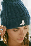 Close up detail front view of model posing in the soft and warm spruce Knit Beanie that has removable custom JOAH BROWN pin.