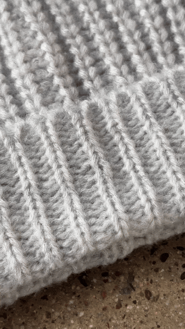 Gif closeup of a handl placing the custom removable JOAH BROWN pin on the front of the soft and warm sterling Knit Beanie 