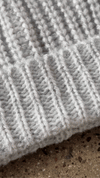 Gif closeup of a handl placing the custom removable JOAH BROWN pin on the front of the soft and warm sterling Knit Beanie 