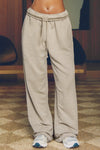 Front view of model from the waist down posing in the relaxed fit sand french terry Oversized Straight Leg Jogger with an elastic waistband, hidden drawstring, pocket details. and adjustable cinching at the ankle cuffs