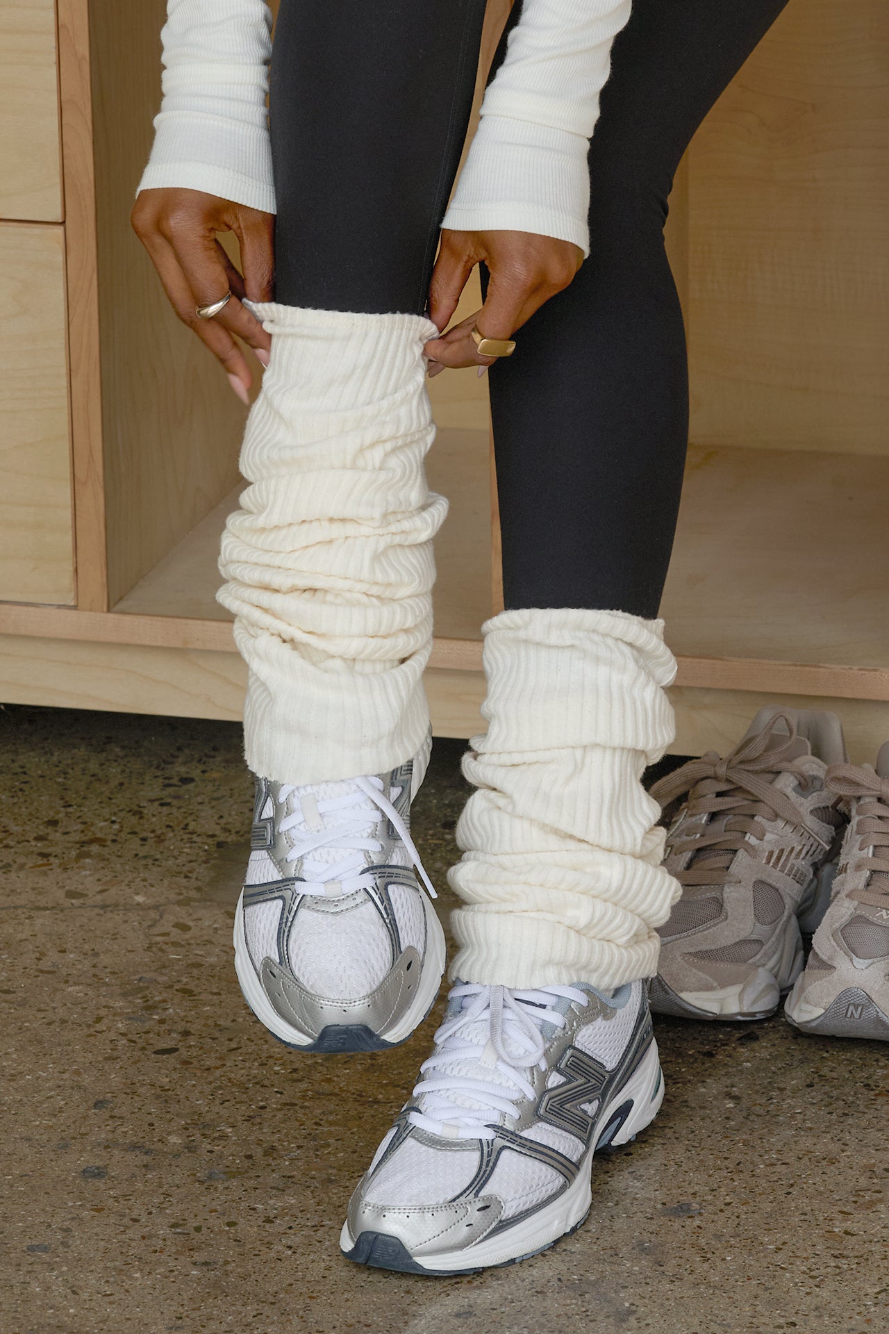 Close up front view of model adjusting the slouchy, pull on natural luxe knit Leg Warmers that can be worn pulled up on scrunched down