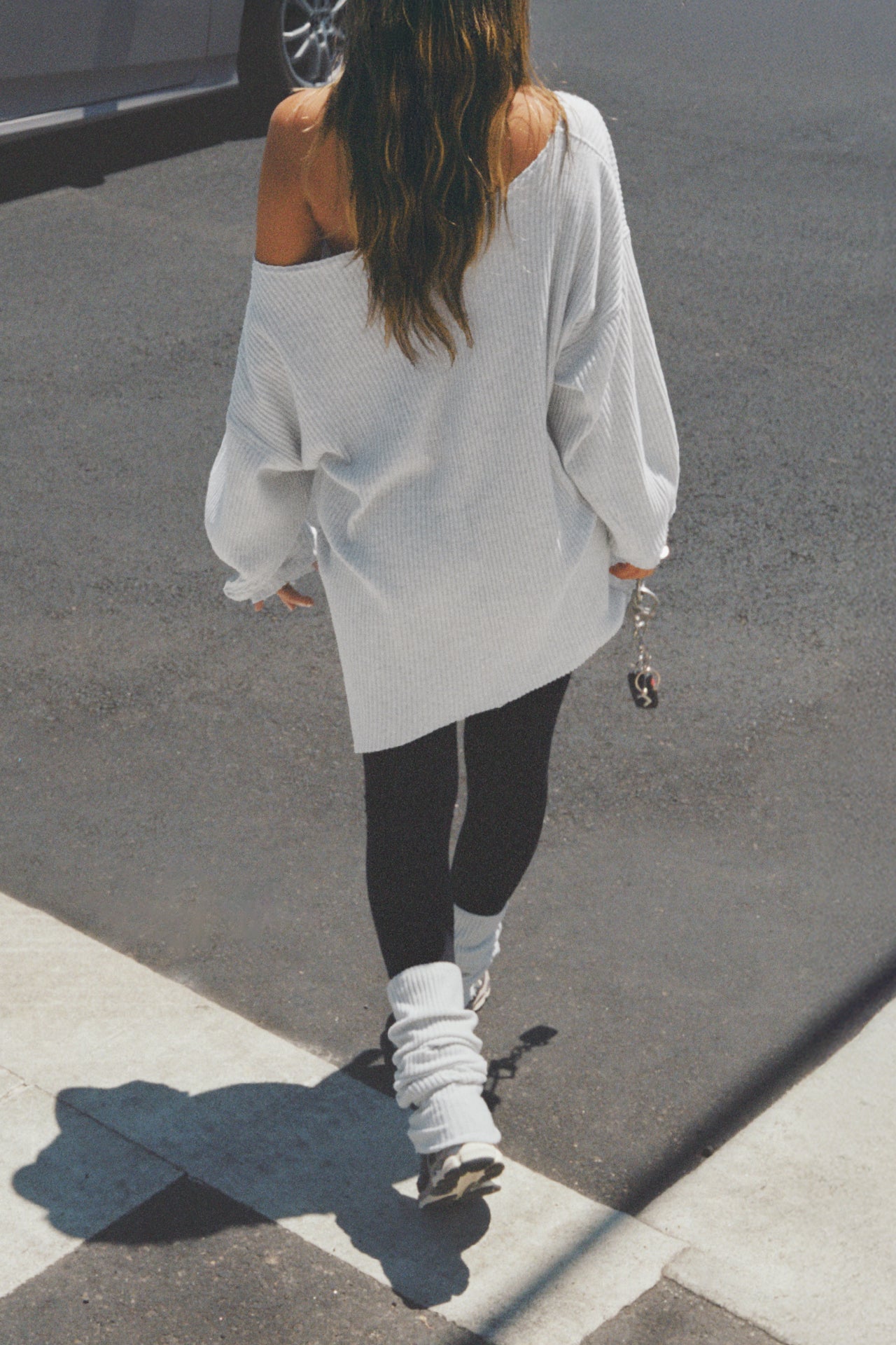 Back view of model walking in the street in slouchy, pull on pearl grey luxe knit Leg Warmers that can be worn pulled up on scrunched down