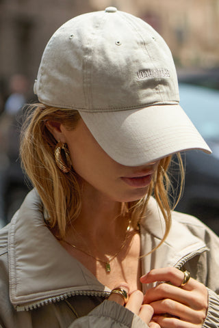 Close up front view of model wearing the six-panel sahara Official Cap with a curved brim and an embroidered upside down Joah Brown logo on the front