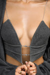 Close up detail front view of model posing in the fitted charcoal luxe knit Cropped Triangle Cami with triangle cup seaming along the bust, thin corded straps and a front center opening banded together with delicate knot buttons