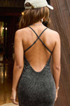 Back view of model posing in the fitted charcoal washed rib Cross Back Midi Dress with an asymmetrical hem, a low scoop back and thin adjustable straps that criss cross in the back