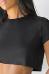 Close up detail front view of model posing in the soft cropped black modal Deconstructed Crop Tee with a crew neckline and exposed seams