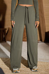 Front view of model from the waist down posing in the relaxed fit spruce modal Relaxed Straight Leg Pant with a wide leg, elastic waistband, adjustable drawstring tie and subtle pleating at the sides.